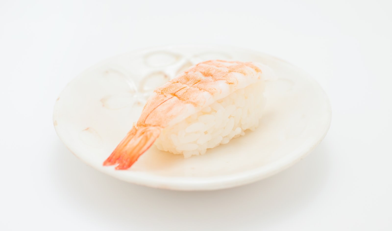 白いお皿に乗ったピンク色の海老のにぎり寿司