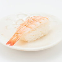 白いお皿に乗った海老のにぎり寿司、新鮮なピンク色のえび握りの写真