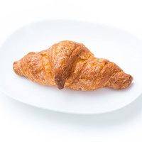 白いお皿にのった焼きたてクroワッサン、層状のパンの写真