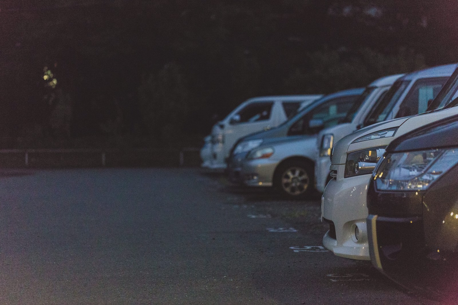 夜間の駐車場に並ぶ複数の車とヘッドライト