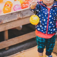 夏祭りの屋台で水風船を選ぶ子供たちの様子の写真