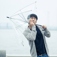 強風で傘が持っていかれそうになる男性の写真