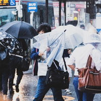 横なぐりの雨で傘が役に立たない駅前の雨の日の写真