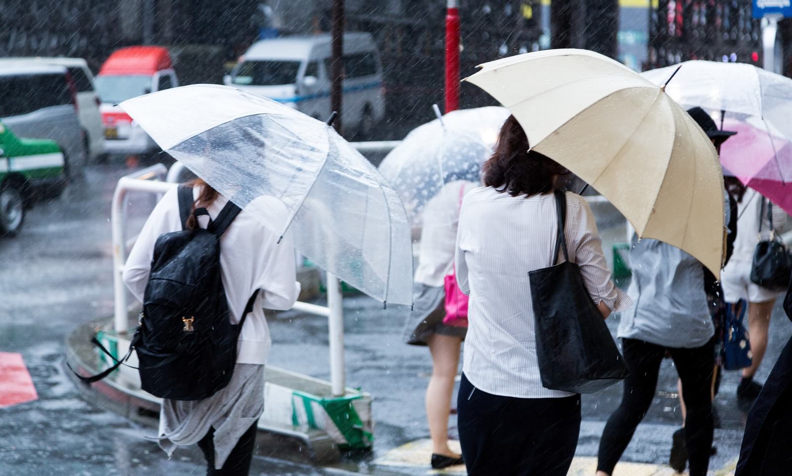 ゲリラ豪雨の中で傘をさして歩く人々