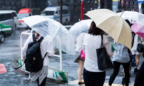 ゲリラ豪雨の中、傘をさして歩く人々の街中での様子