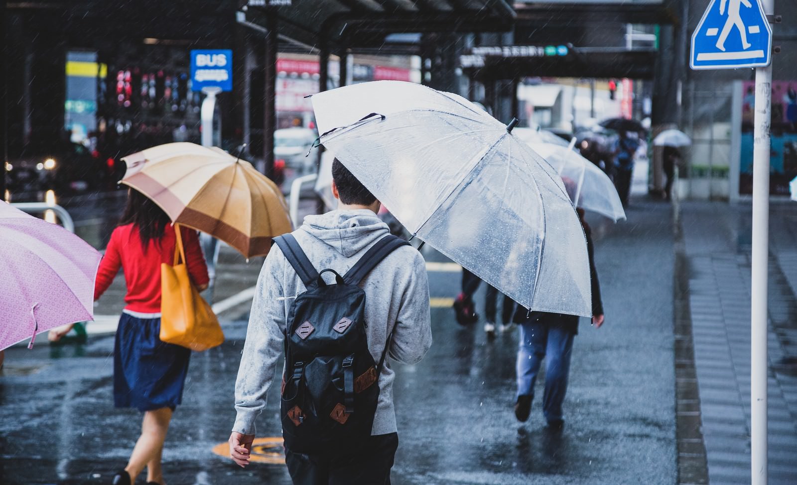 雨の街中で傘をさして歩く人々