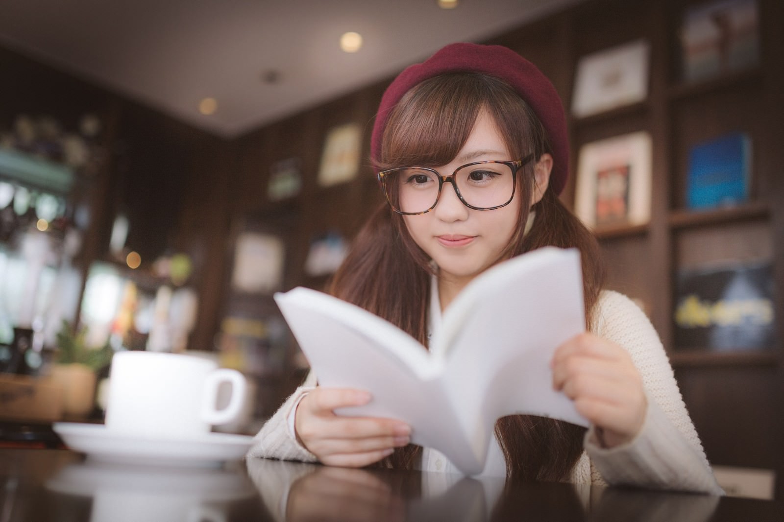 メガネをかけてカフェで書類を読む女性［モデル：河村友歌］
