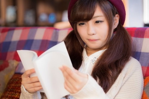 新刊の雑誌をソファーで読むベレー帽の女性