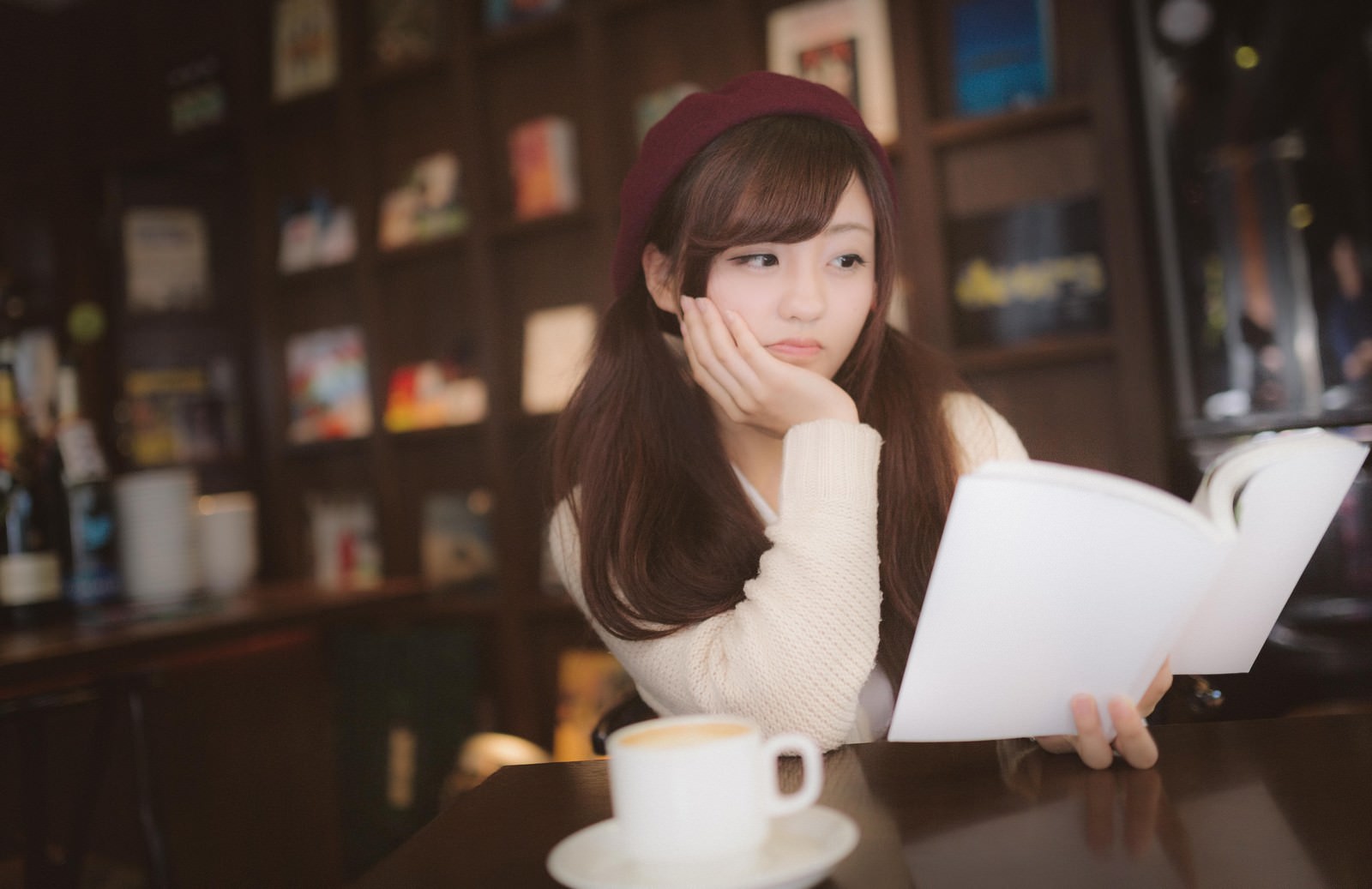 カフェで本を読んでがっかりする赤いヘアバンドの女性［モデル：河村友歌］