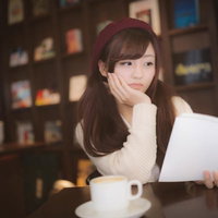 カフェでコーヒーを飲みながら購入した本にがっかりする美女の写真