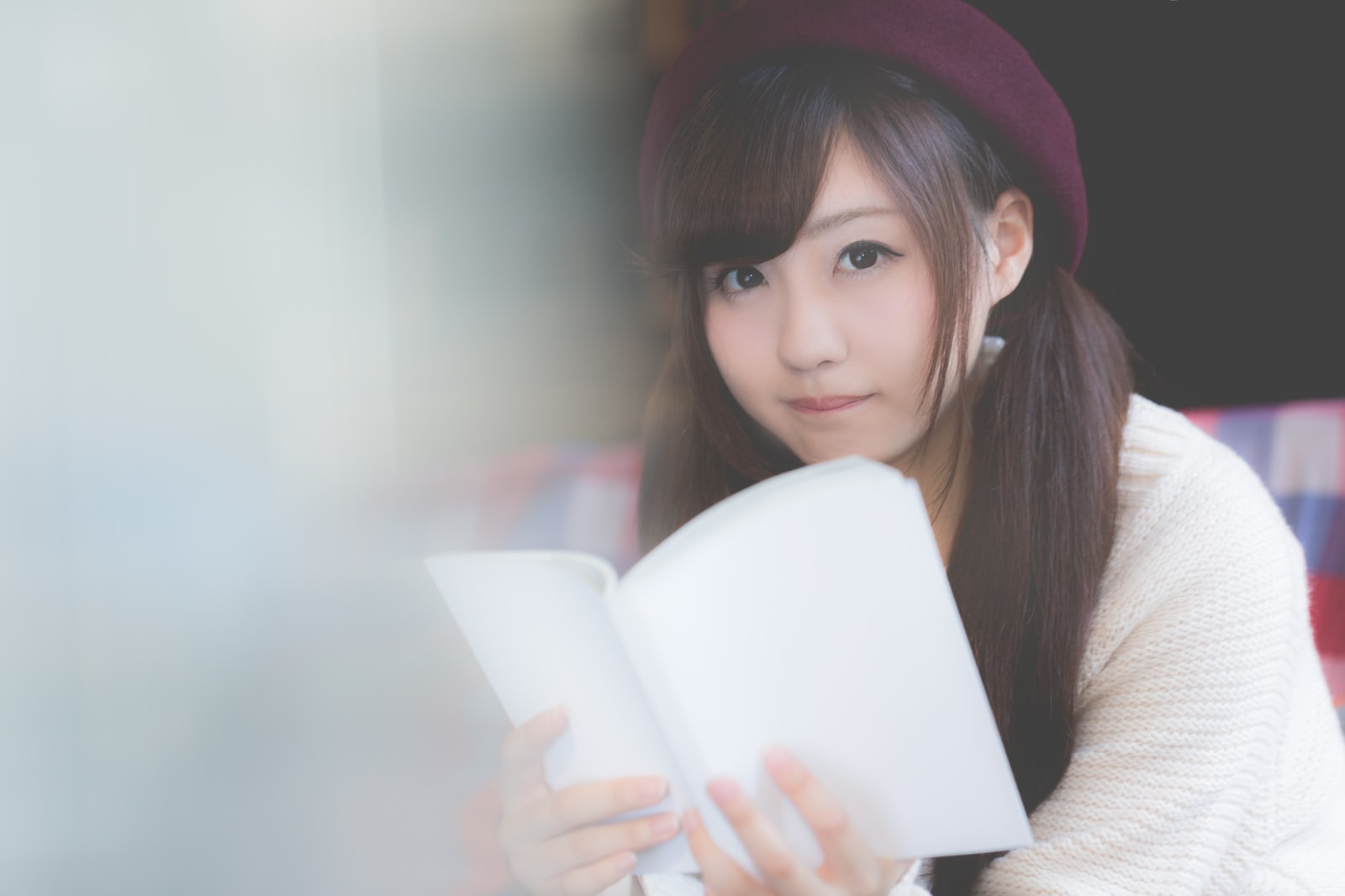 ベレー帽をかぶり、ニットを着てマンガを読む女性［モデル：河村友歌］