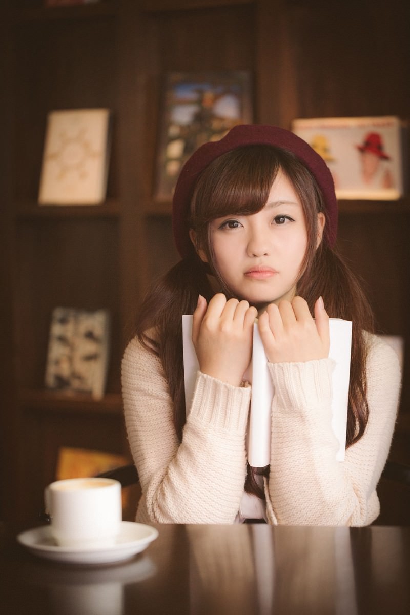 カフェでベレー帽をかぶり本を抱きしめて読む女性［モデル：河村友歌］