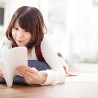 マンガのワクワクする展開に思わず笑みがこぼれる女性の写真