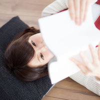 新刊を寝転びながら読んでいる美少女のリラックス読書シーンの写真