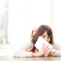 本を顔に当てて照れ笑いする女性、あっという間に全巻読破の写真