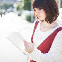 街中で読書する美女、白い服と赤いカバンでおしゃれに本を読むの写真