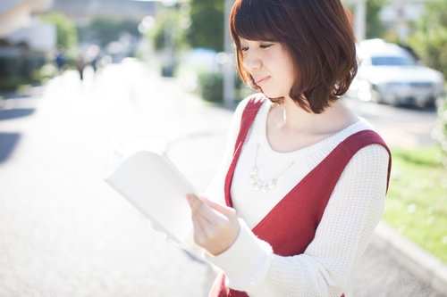街中で読書する美女、白い服と赤いカバンでおしゃれに本を読む