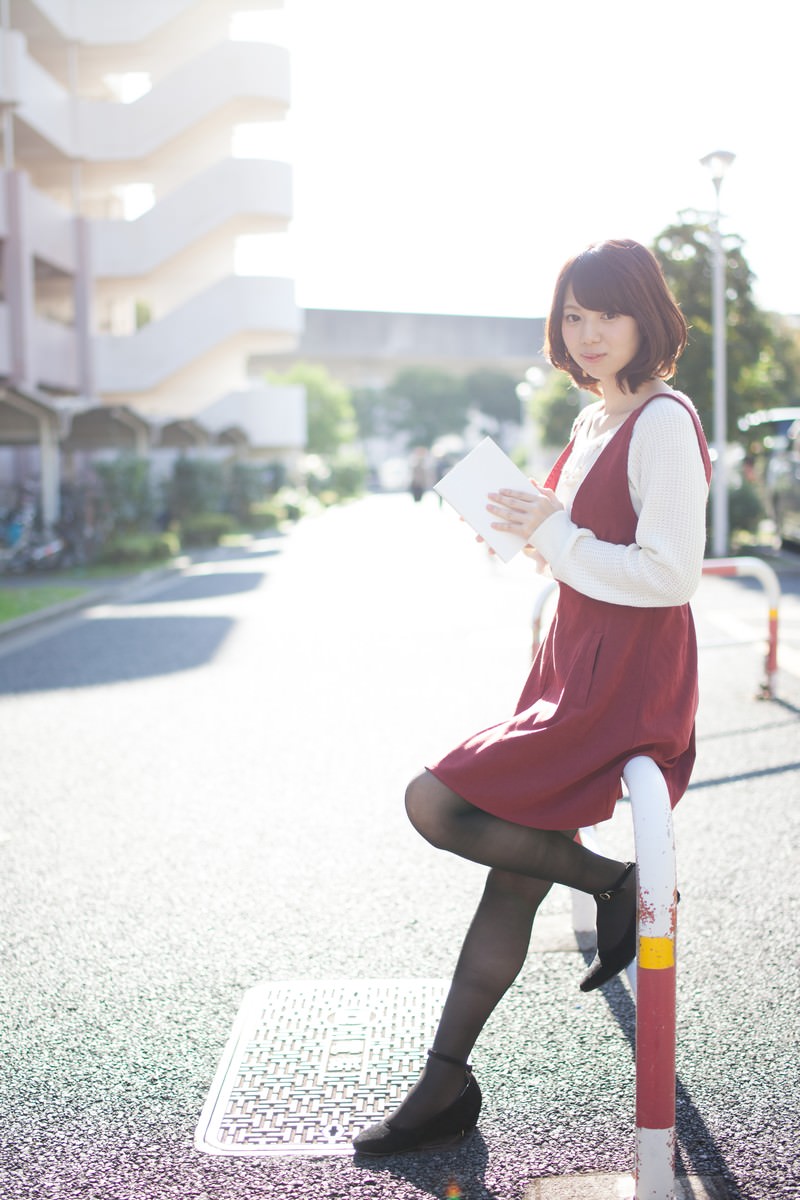 駐車場で本を読みながら立つ女性［モデル：みき。］