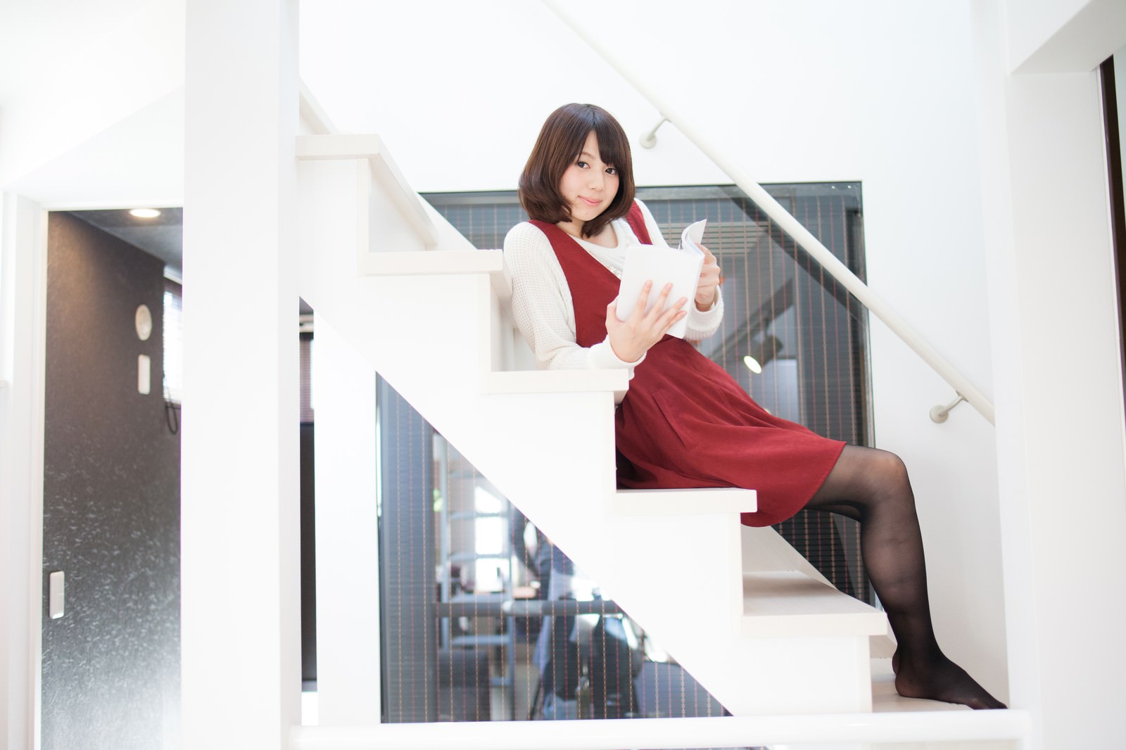 新築の家の階段で漫画を読む女性［モデル：みき。］