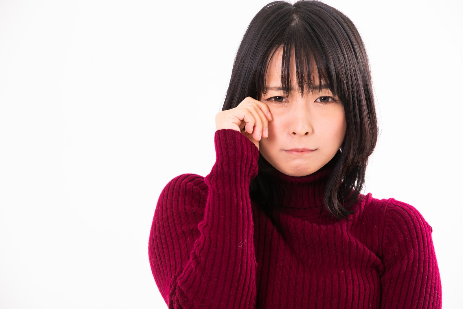 赤いセーターを着た女性が手で顔を覆い泣きそうな表情をしている［モデル：にゃるる］
