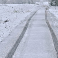 人のいない雪道に残る車のタイヤ痕と冬の風景の写真