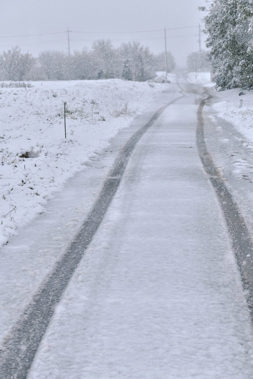 人のいない雪道に残る車のタイヤ痕と冬の風景