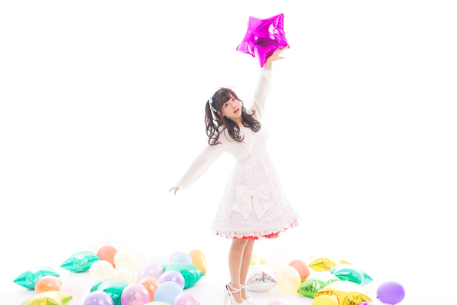 白いドレスを着た女性アイドルが星型の風船を持ち、カラフルな風船に囲まれている様子［モデル：河村友歌］