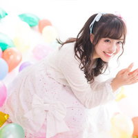 カラフルな風船に囲まれて笑顔を見せる女性アイドルの写真