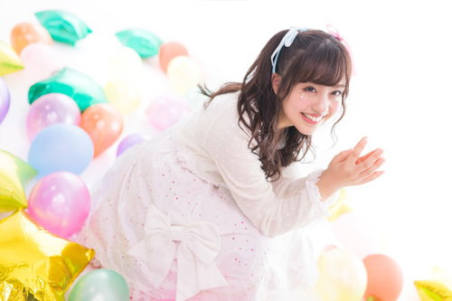 カラフルな風船に囲まれて笑顔を見せる女性アイドル