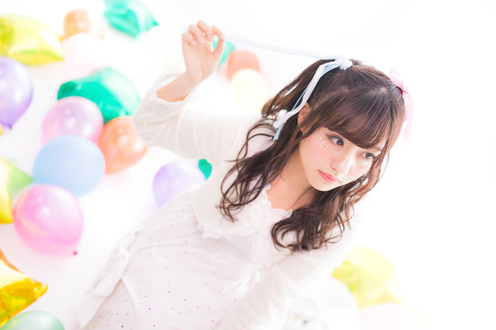 白い衣装を着た女性アイドルがツインテールのリボンを解こうとしている写真［モデル：河村友歌］