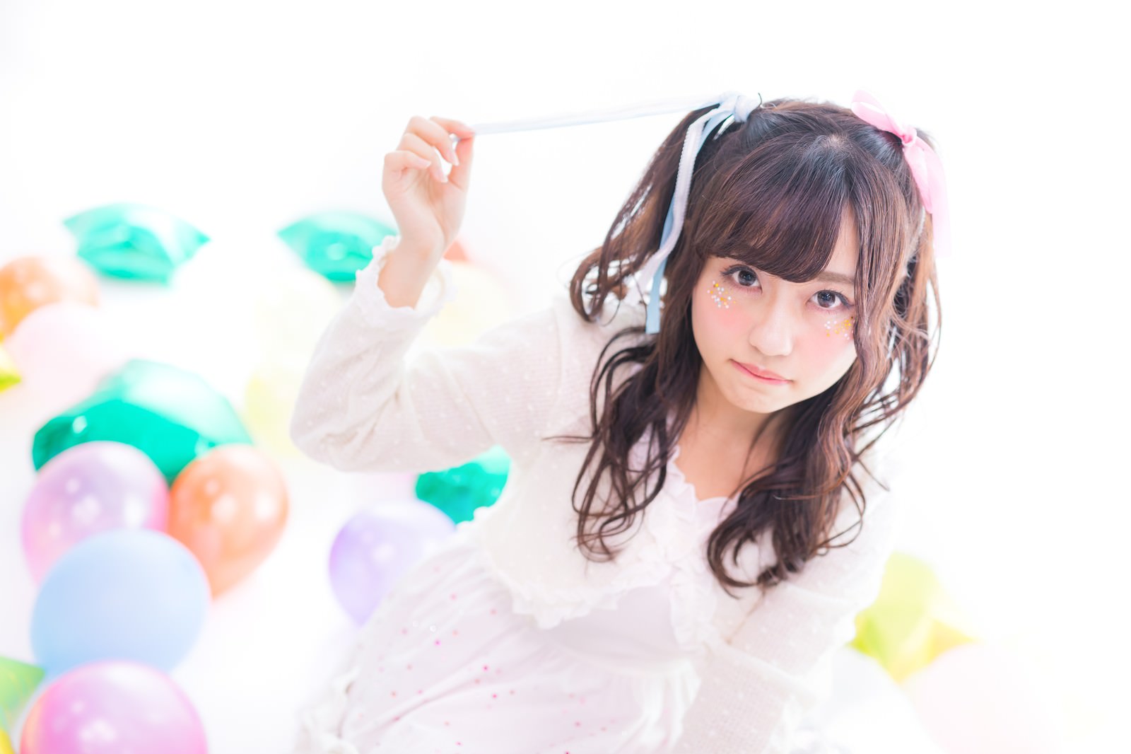 白いドレスを着たツインテールの女性が風船の前でポーズをとっている［モデル：河村友歌］
