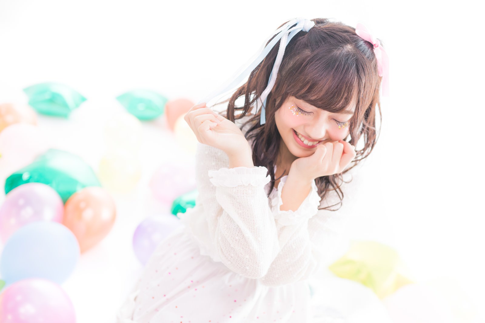 カラフルな風船の前で恥ずかしそうに微笑むツインテールの女性アイドル［モデル：河村友歌］