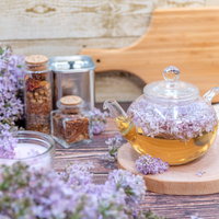 木製テーブルに溢れるライラックとティーポットの写真