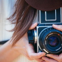 ハッセルブラッドのフィルムカメラを持って撮影する女性の写真