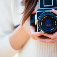 手持ちのクラシックカメラで撮影準備する女性の写真