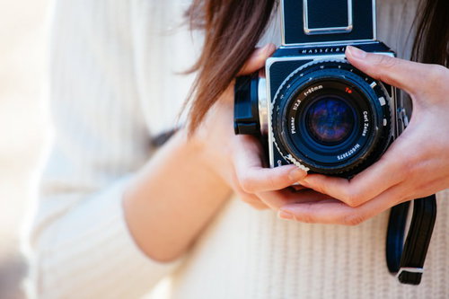 手持ちのクラシックカメラで撮影準備する女性