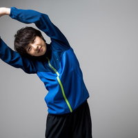 青いスポーツウェアでストレッチをするトレーニング中の女性の写真