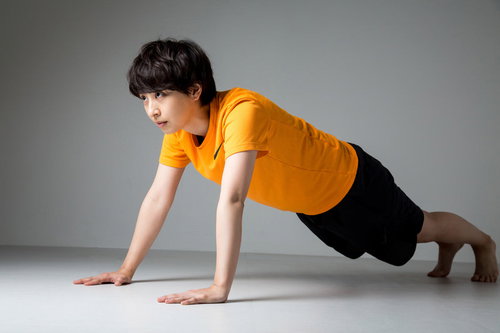 オレンジシャツで腕立て伏せをするスポーツ女子