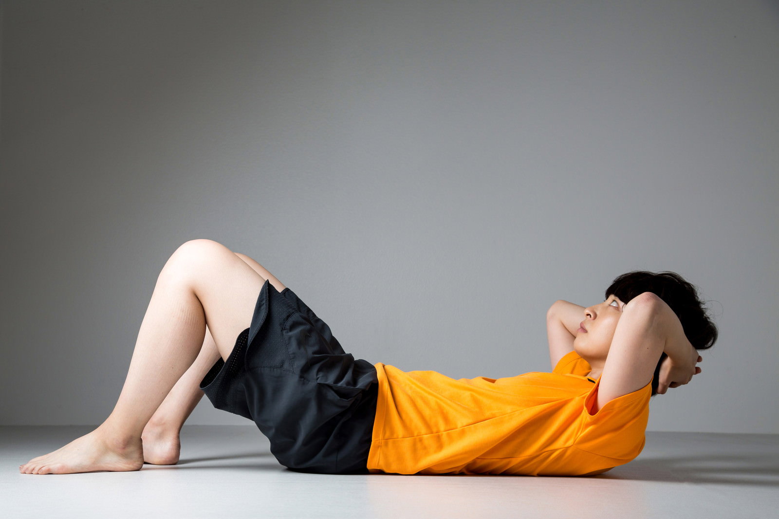 床で腹筋運動をする子ども［モデル：八木彩香］