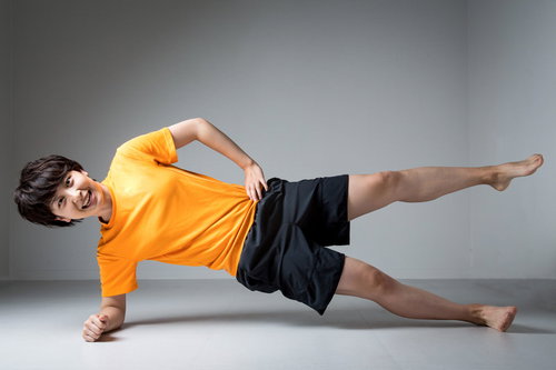 笑顔でサイドプランクするトレーニング男性インストラクター