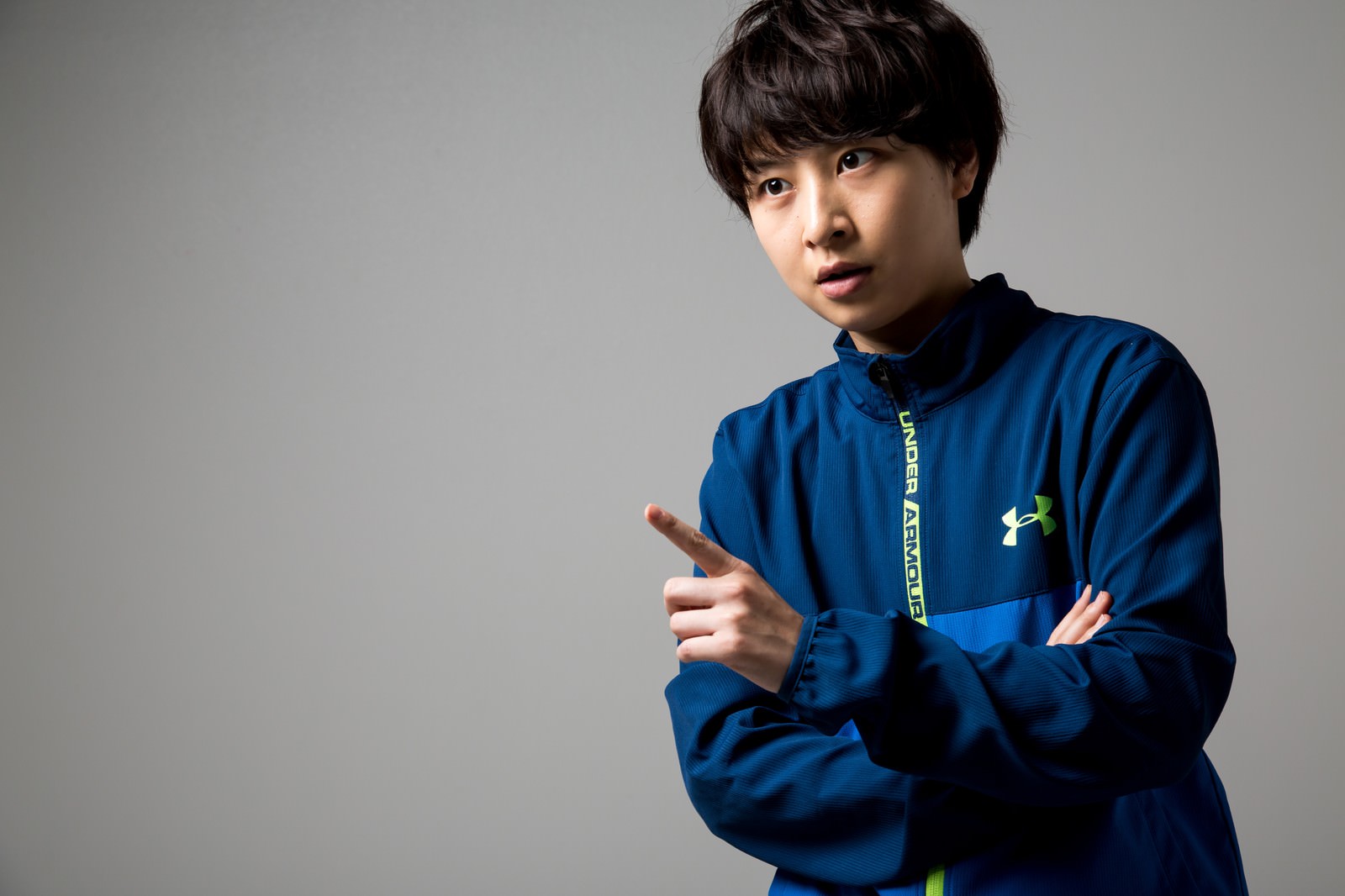 青いジャージで手を指し出し説明する女性トレーナー［モデル：八木彩香］