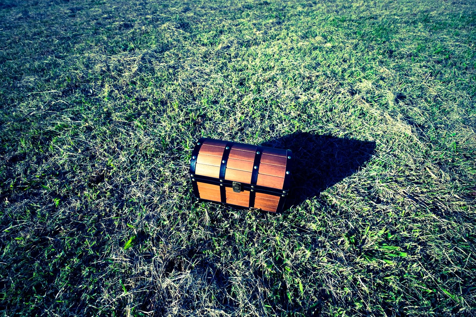 緑の草原に茶色の木製宝箱が一つ置かれている風景