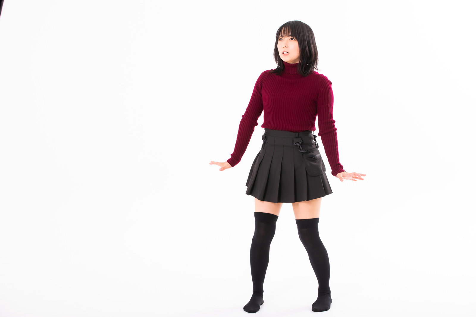 A woman in a red sweater and checkered skirt backing away with her hands extended