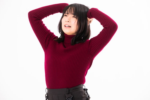 赤いセーターを着て頭を抱えて後悔する女性