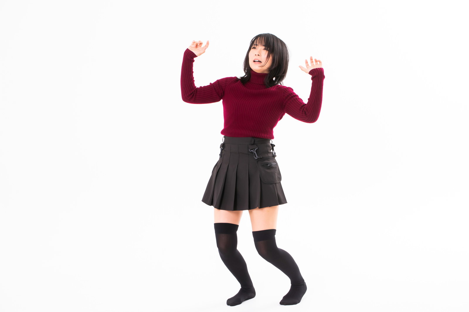 両手を上げて後退りする赤いトップスと黒いスカートの女性［モデル：にゃるる］
