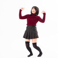 赤いトップスで両手を上げて後退りする女性の写真