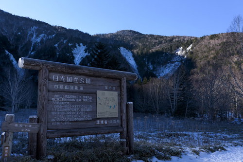 冬の日光白根山登山口に立つ木製の案内看板