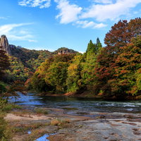 色づきはじめる渓谷の紅葉と清流の写真