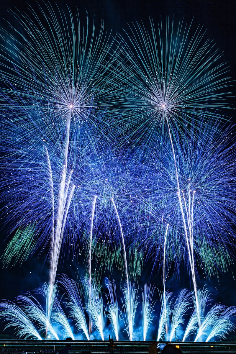 夜空に青色のスターマインが放射状に広がる花火の様子