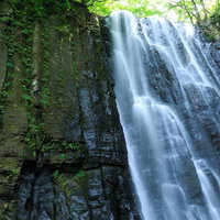 柱状節理の岩壁から流れ落ちる滝と渓流風景の写真